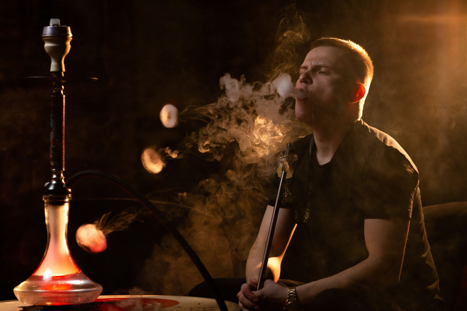 young man vaping from hookah bar