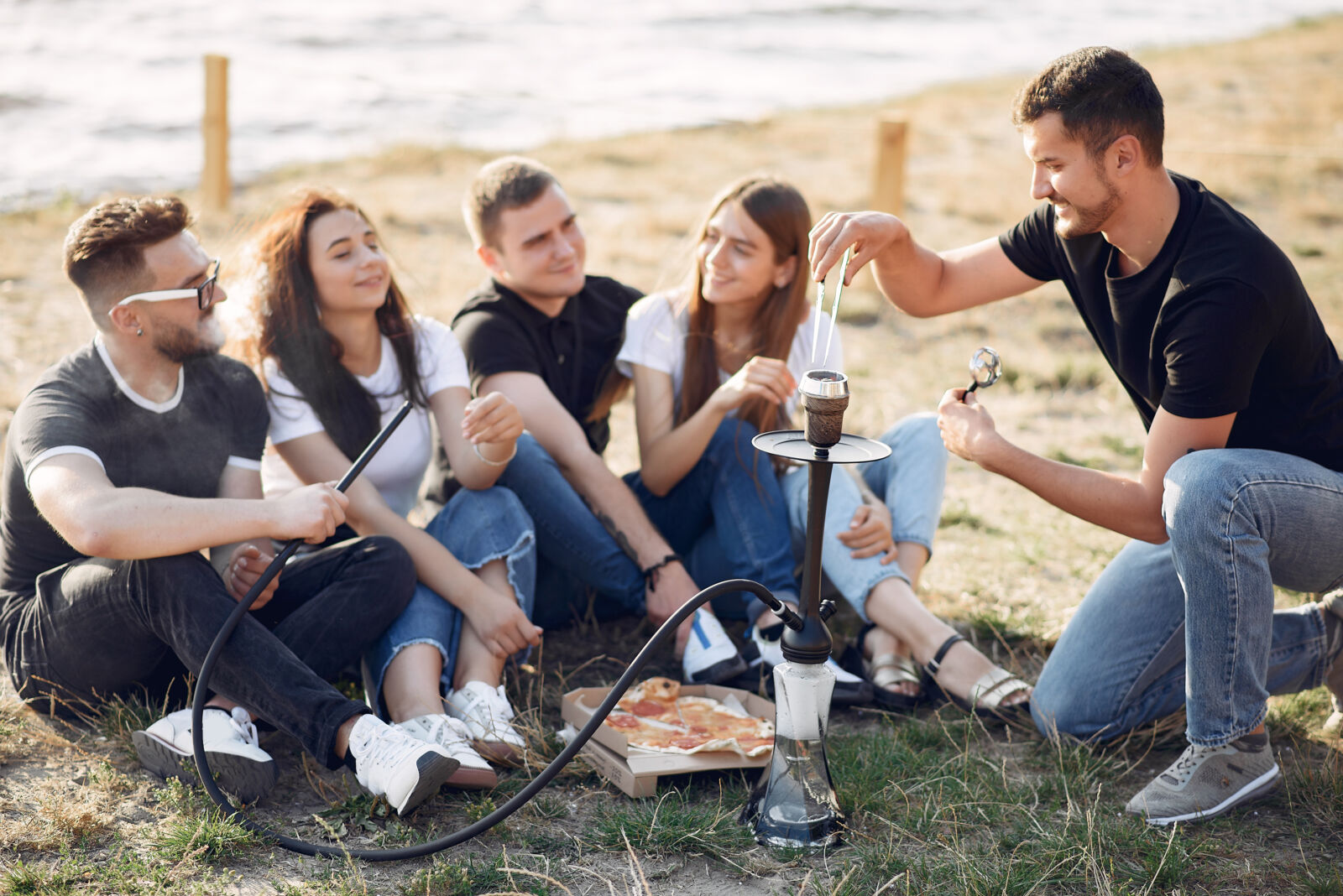 Friends enjoying outdoor picnic with hookah and pizza